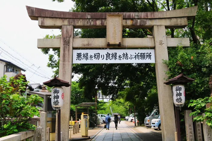 参道の入口に立つ木の鳥居と提灯